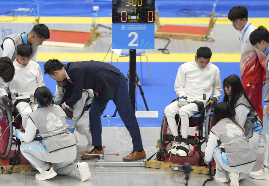 Referees and volunteers helping athletes secure their wheelchairs before the competition.